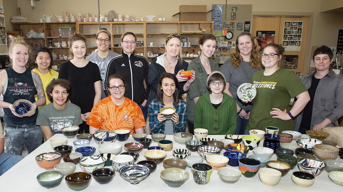 Community table participants gathered for a group photo around handmade pottery