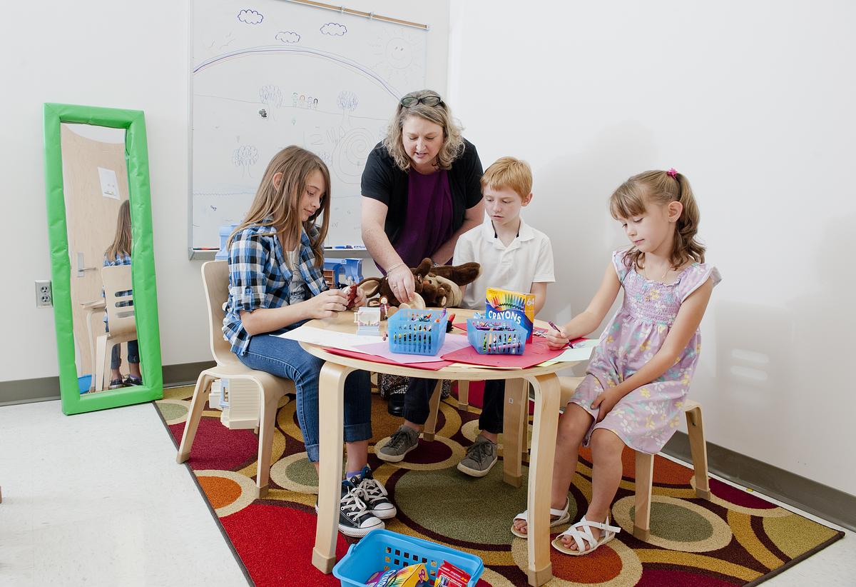 Teacher showing young children something at a table in class