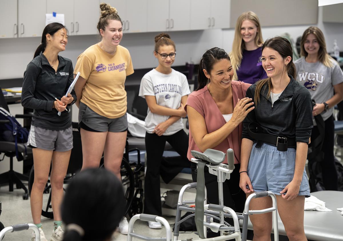 Professor working with a person for a physical therapy class demonstration with everyone smiling and laughing together