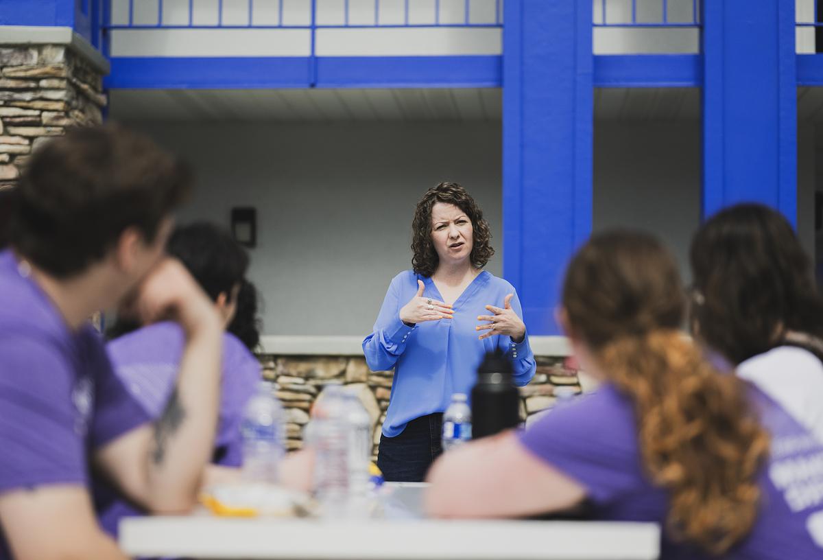 Service learning staff and volunteers listening to a women speak outside at a worksite