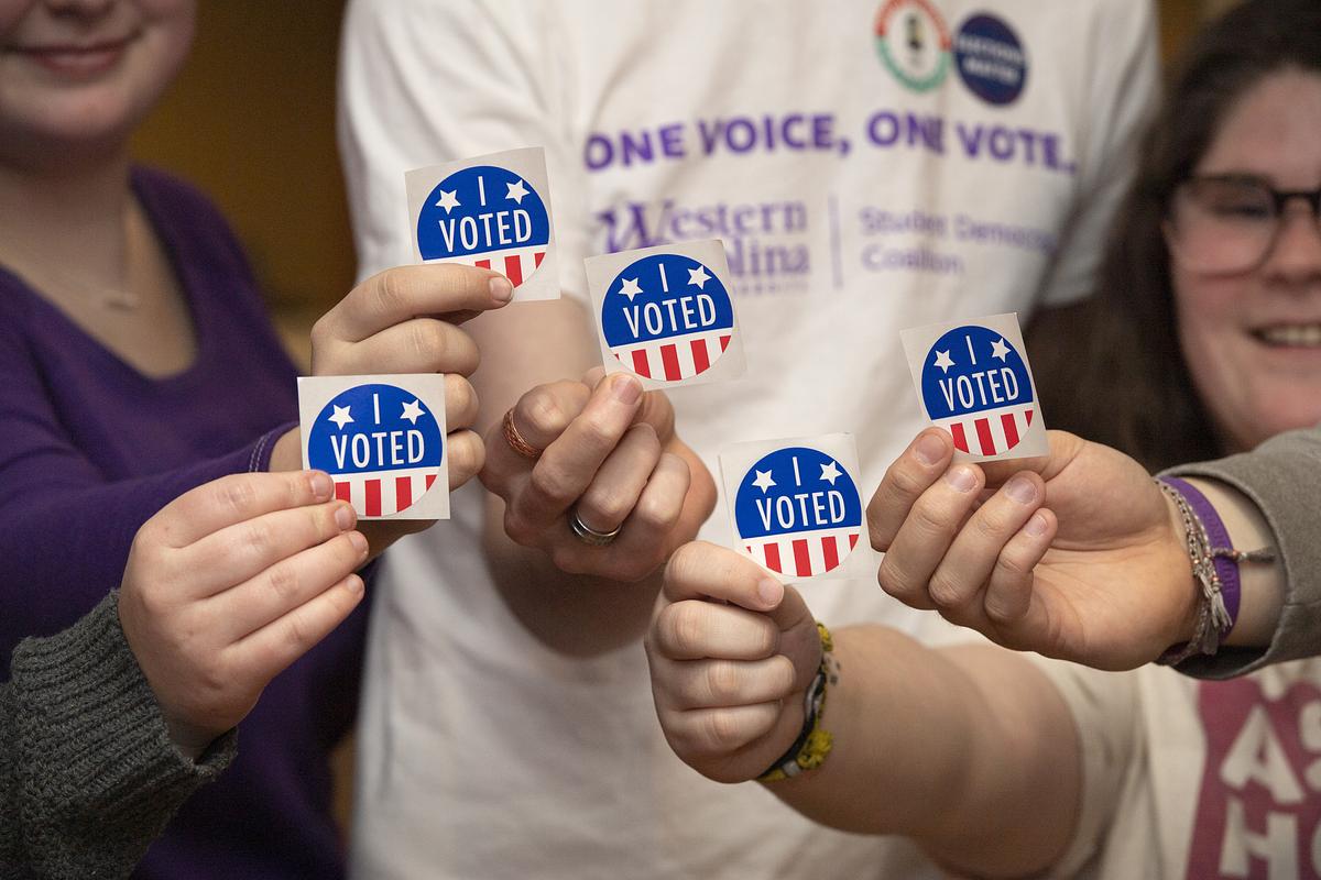 Students holding I Voted stickers up together