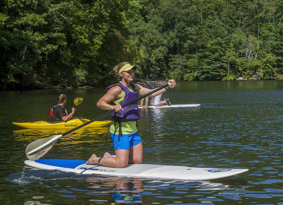 Kayaker and paddle boarders in the water on a beautiful summer day