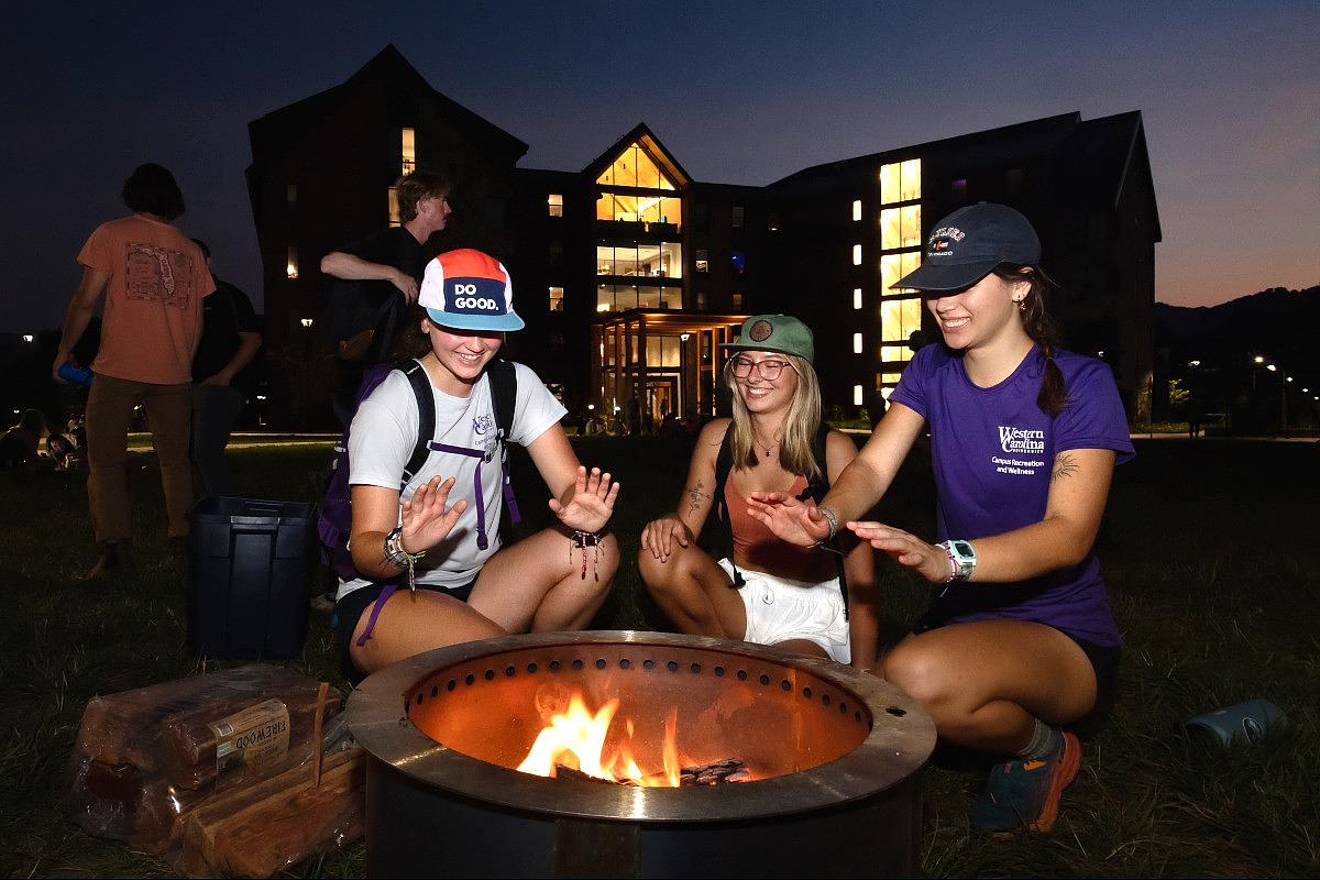 Students warming their hands around a fire pit