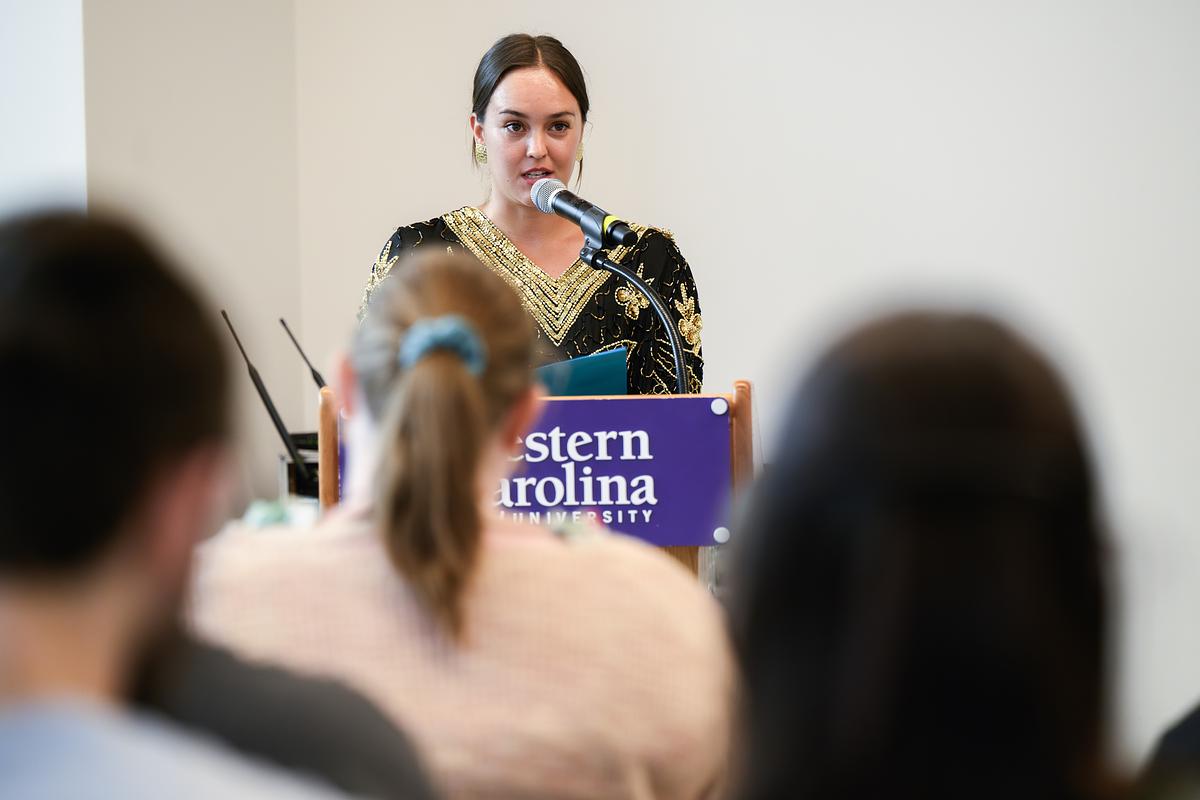 English Masters student giving a presentation at a podium in front of an audience