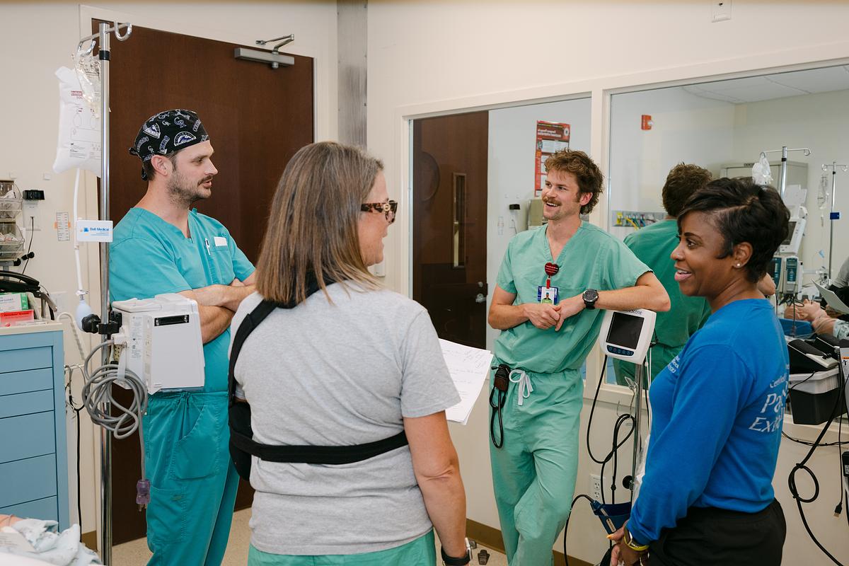 Male nursing students in lab talking with 2 female teachers