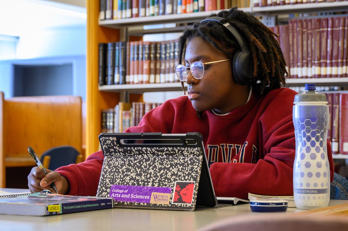 Student sitting at a desk working with their headphones on