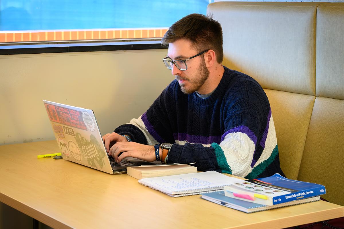 Student working with their laptop at a booth in the Hunter Library