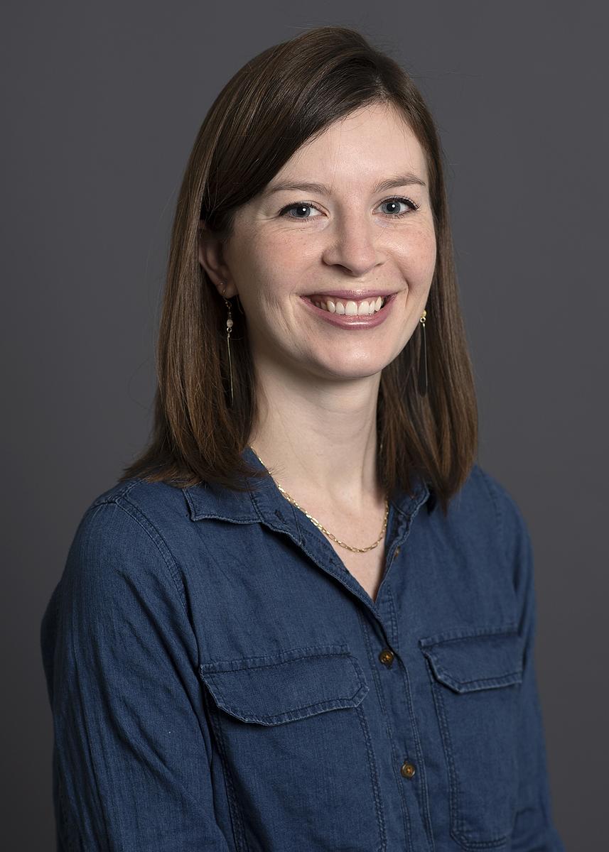 Amanda Lytle, a smiling woman with shoulder-length dark brown hair wearing a blue denim shirt.