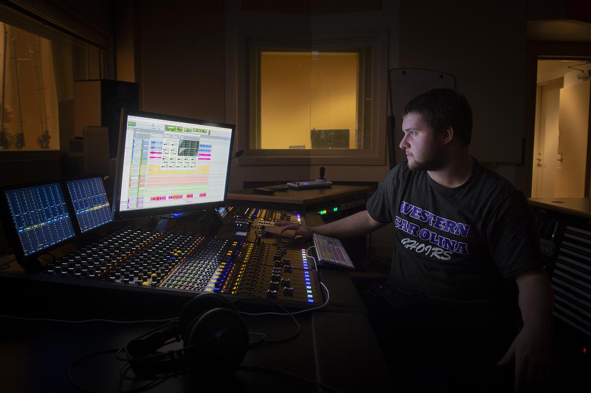 Student sitting at the main control board for a musical production