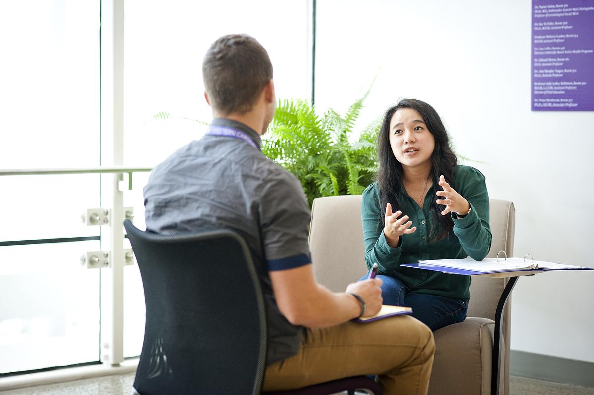 Social work faculty sit and talk together in a lobby