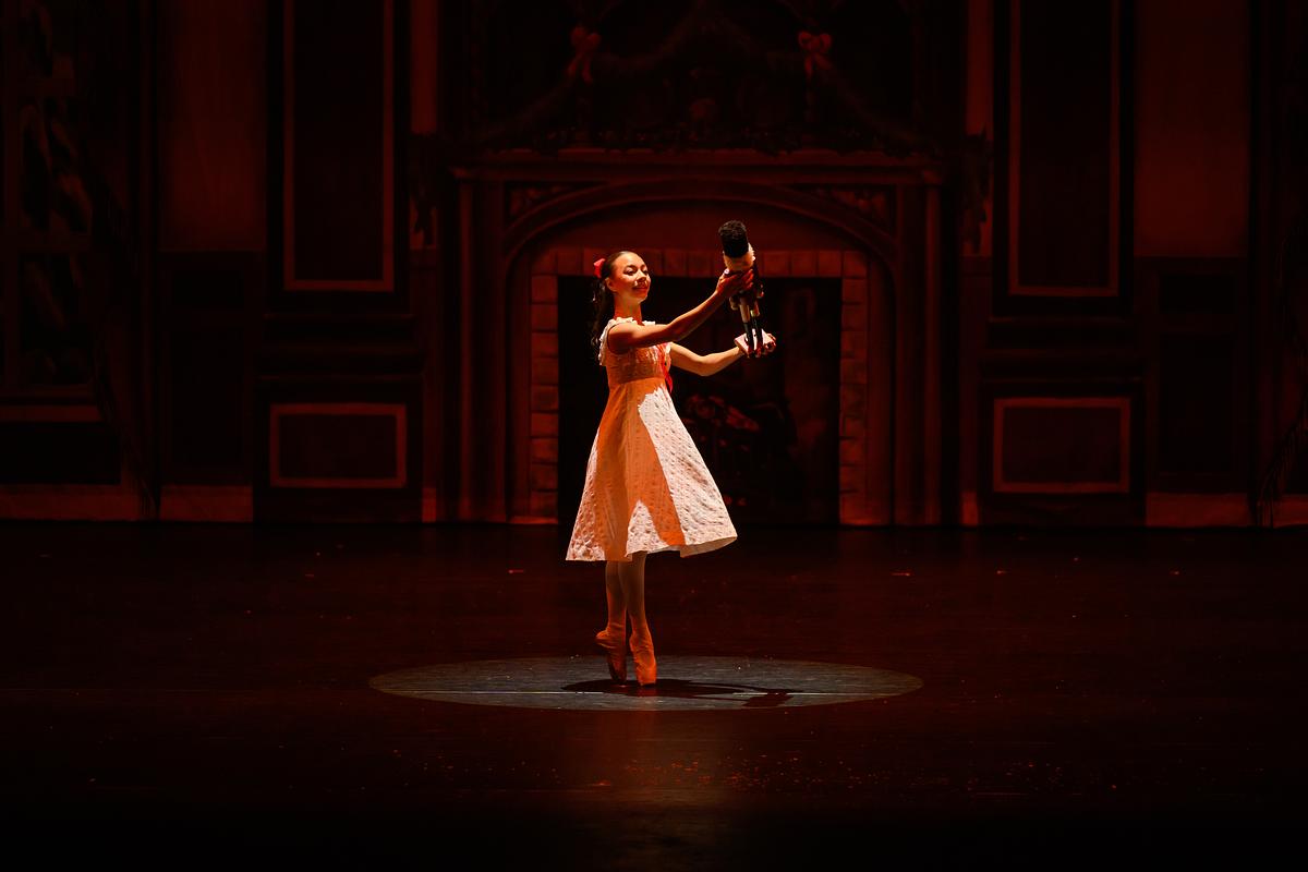 Student dancing on stage holding a prop during a live performance of the nutcracker