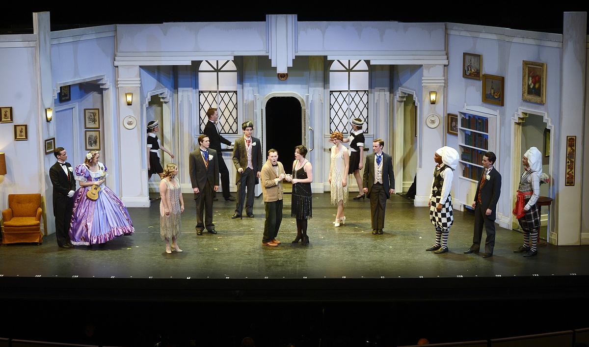 Students performing a show on stage with various props and outfits