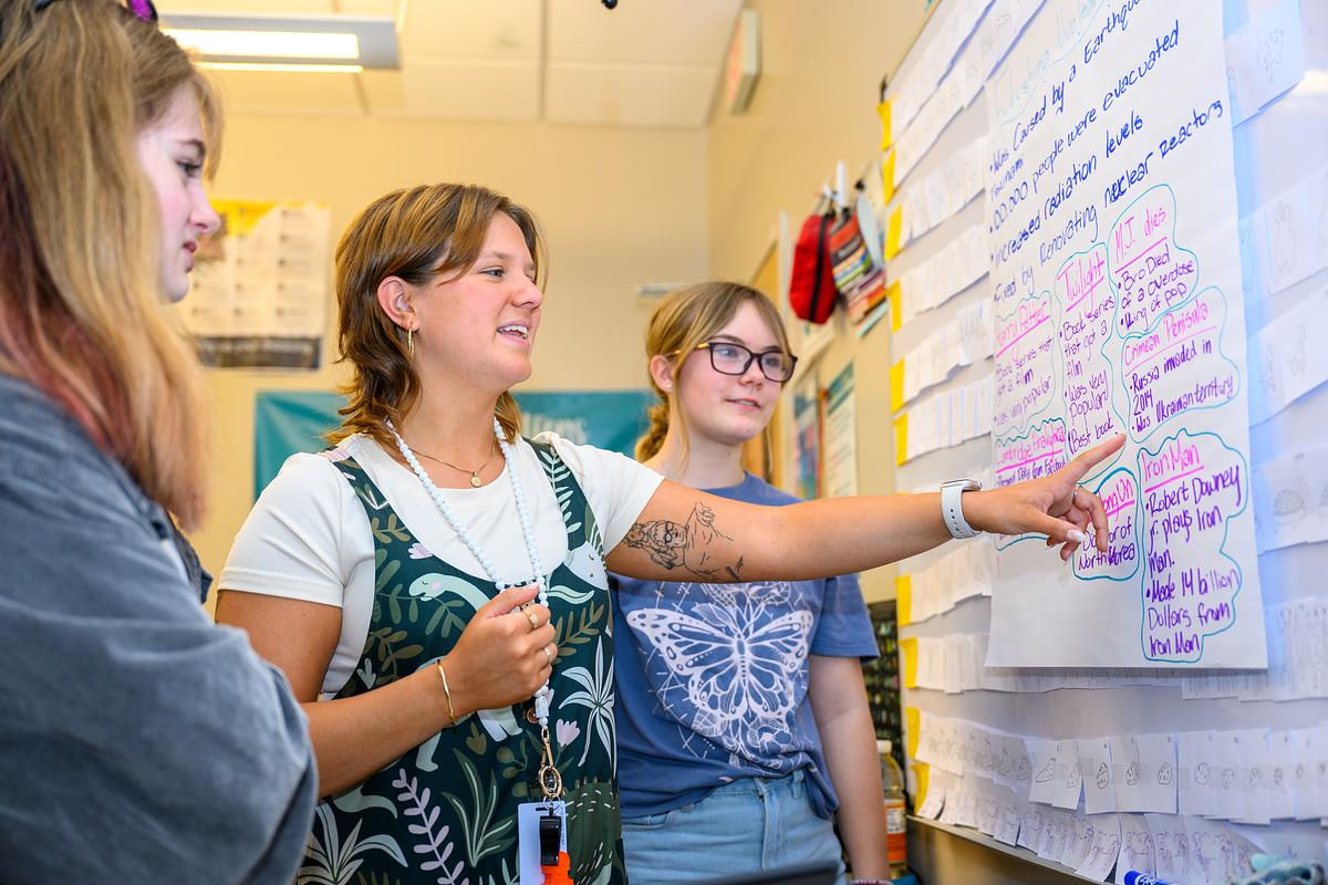 Student intern teaching students in class demonstrating on a whiteboard