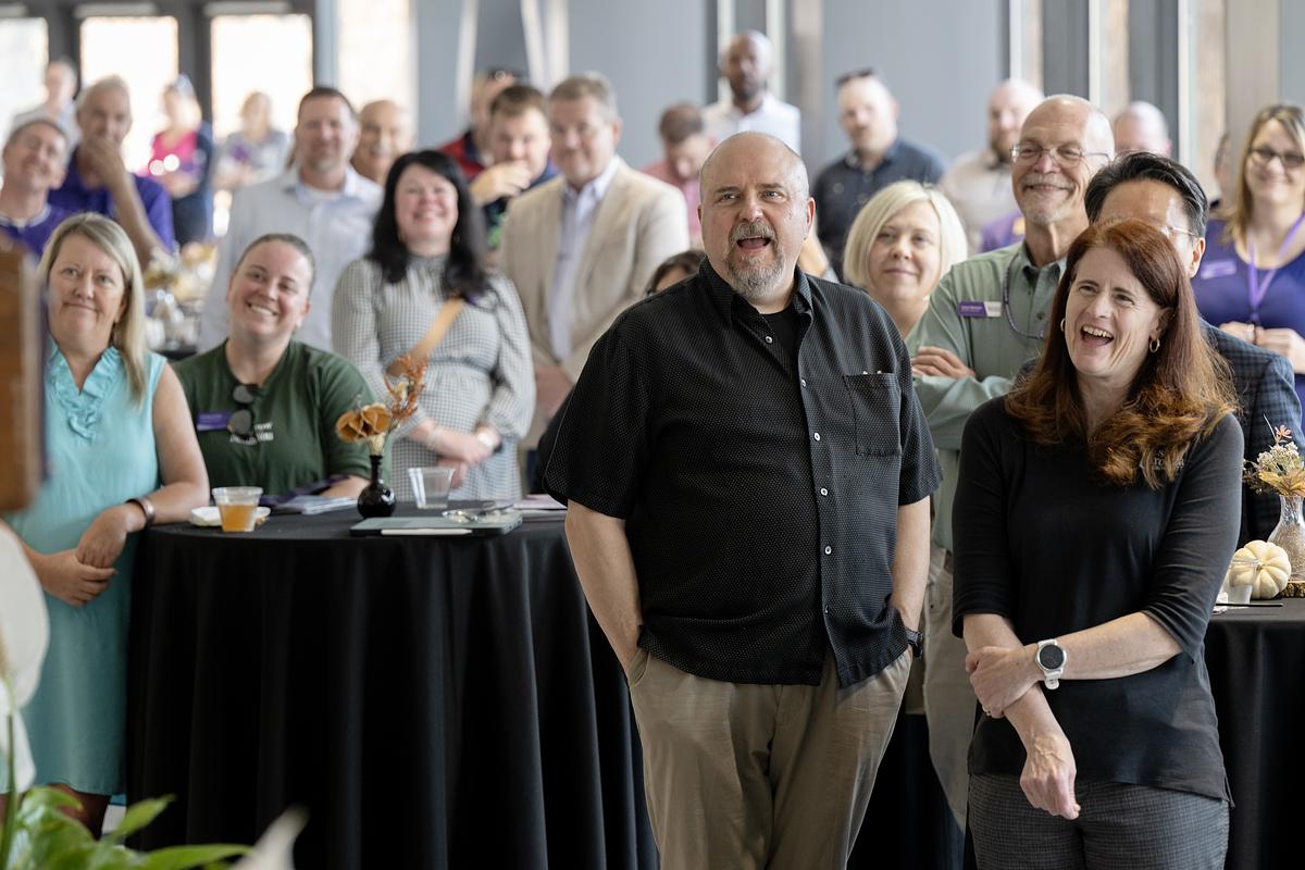 Image of multiple people standing facing the speaker on the podium