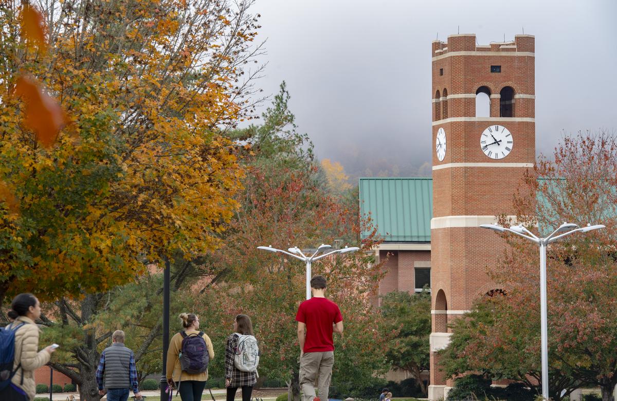 Students walking around campus with the Alumni tower in the background