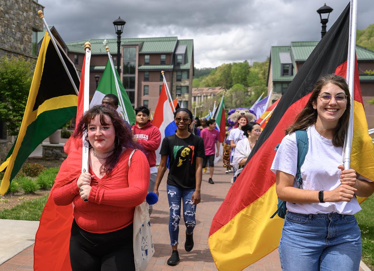 Students walking on campus together for the international festival holding various flags