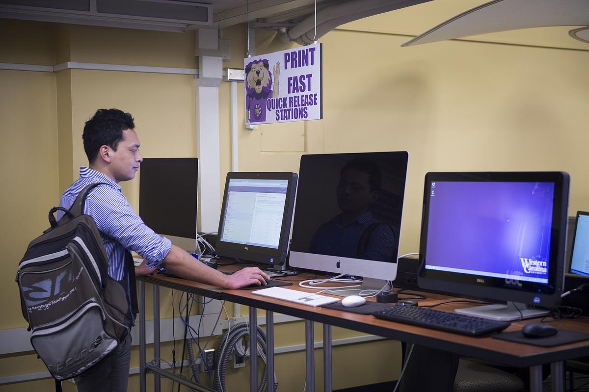 Student standing at a computer desk in Hunter Library at the Technology Commons