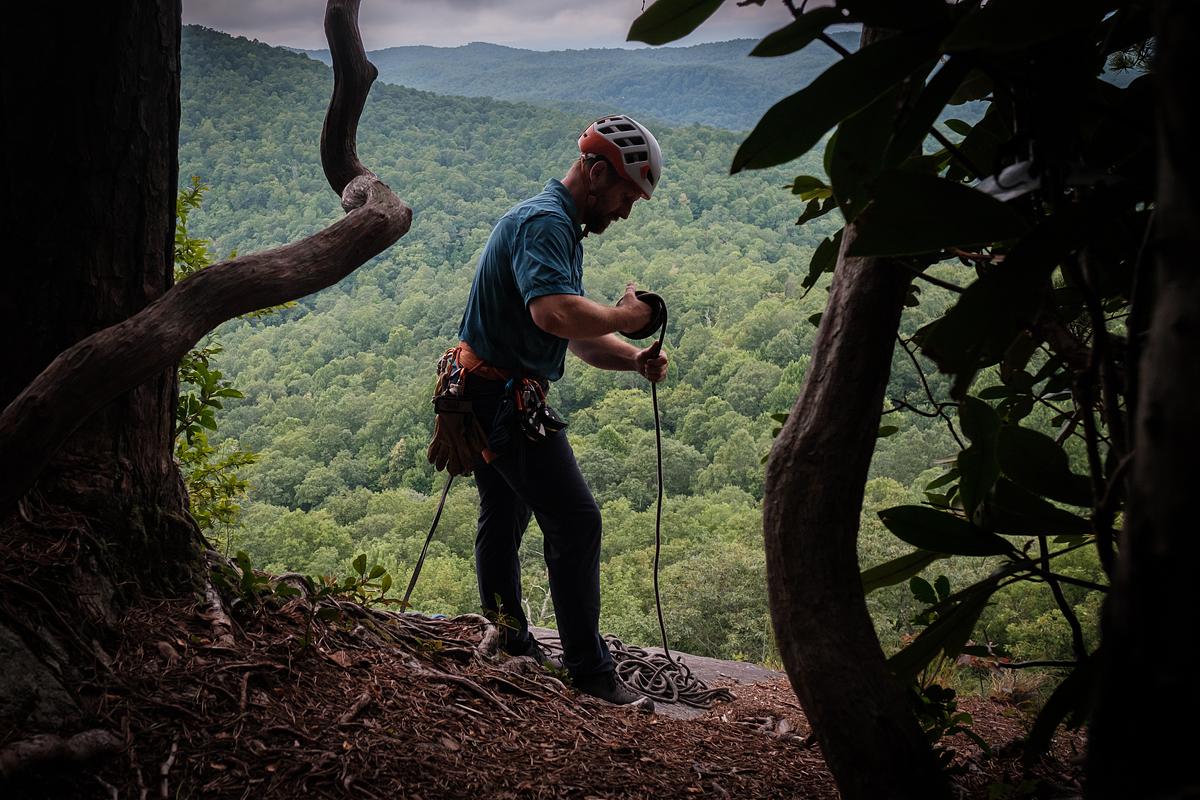 Climber at the top of a rock face and overlook organizes the climbers rope