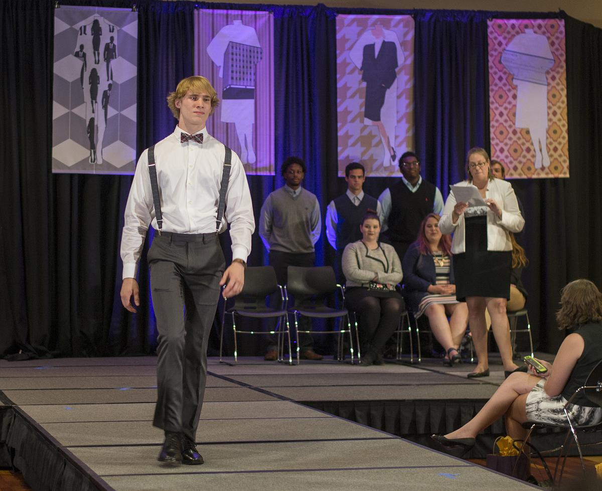 Picture of a young man at a fashion show on a runway.