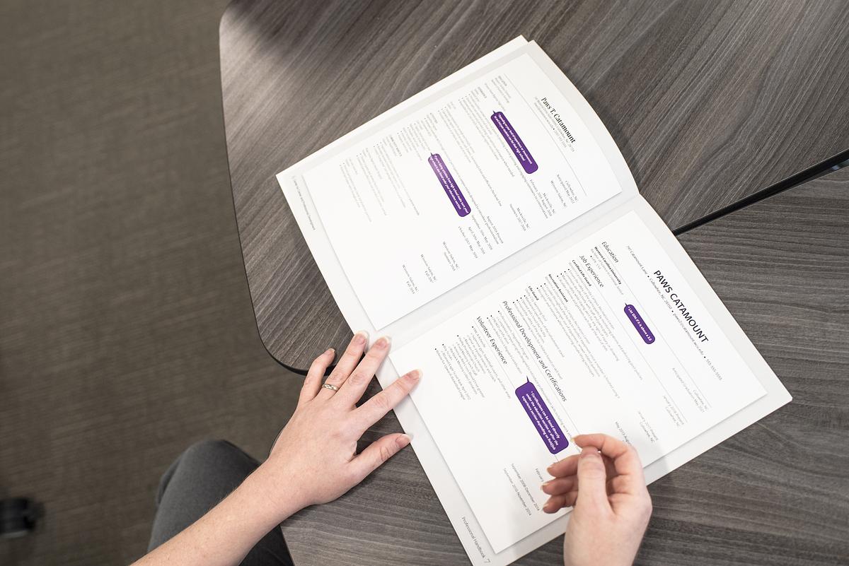 Individual looking at a handbook at a table