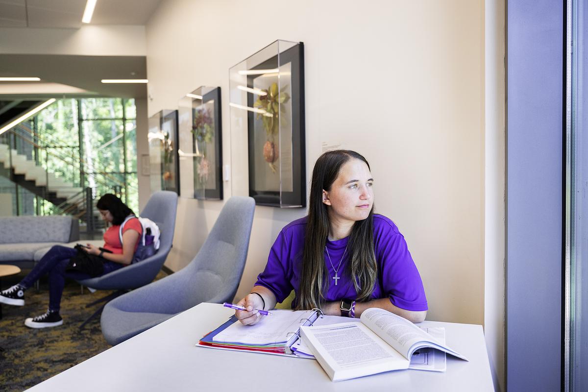 Students studying in a lounge smiling as they look out of a window