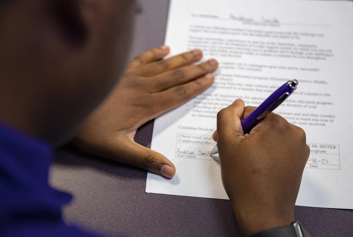 Photograph of a MiSTER signing a document