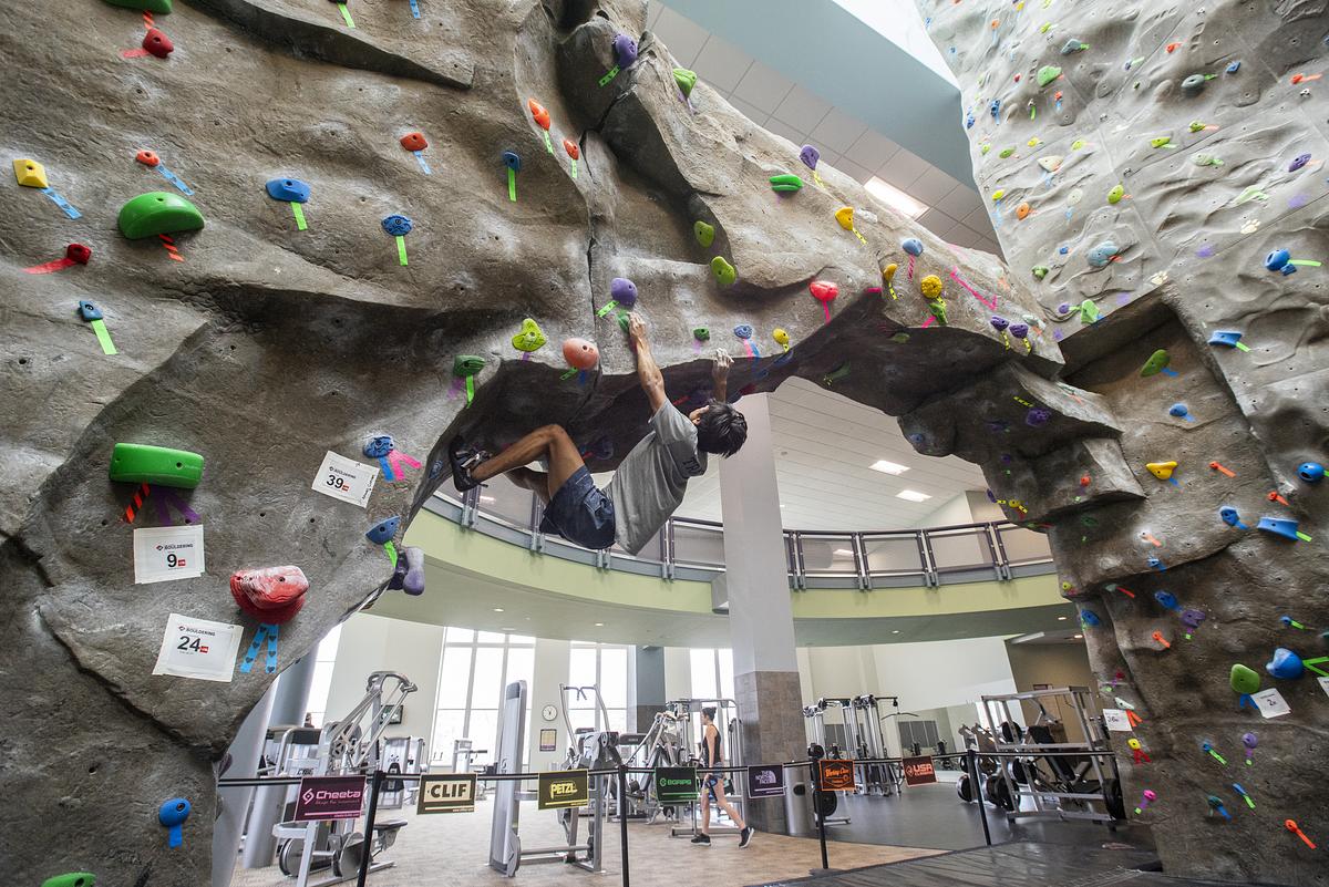 Student in the CRC attempting a move on the rock climbing wall