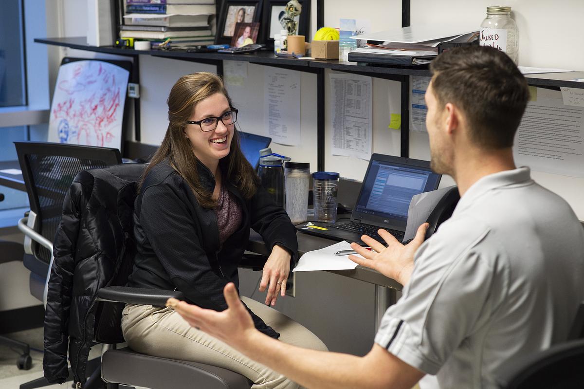 Staff and faculty sitting down at a desk in discussion
