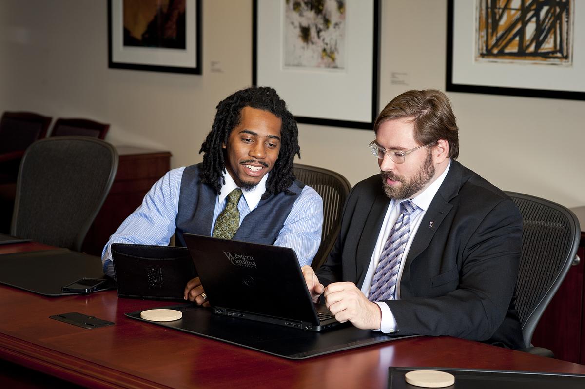 College of business students looking at a laptop together at a table