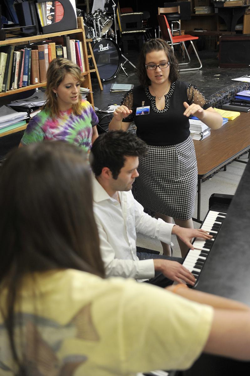 Teachers performing a song on the piano and teaching students the process
