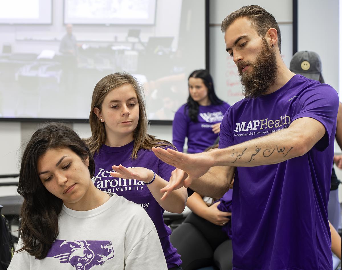 Teacher showing physical therapy students how to administer a physical therapy stretch