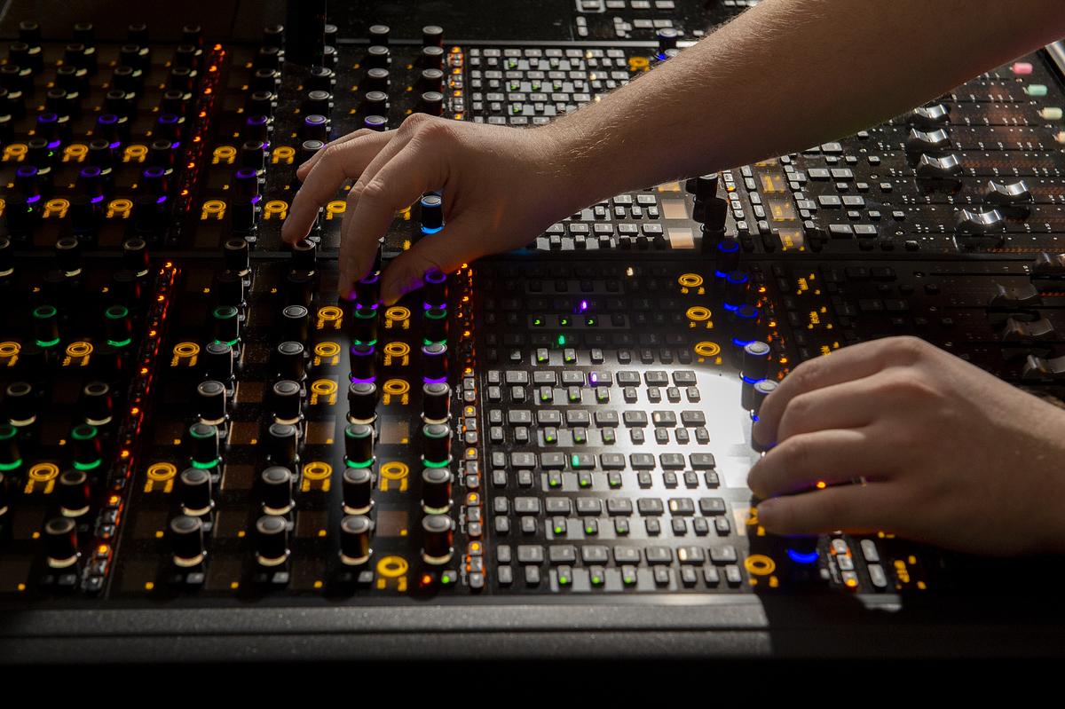 Student adjusting dials on a commercial music soundboard