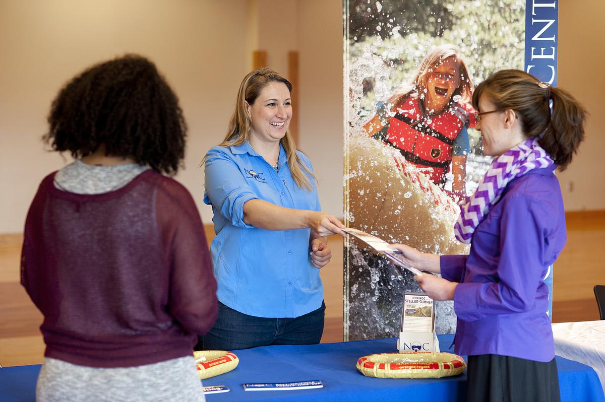 A woman hands out brochures at Career Fair.