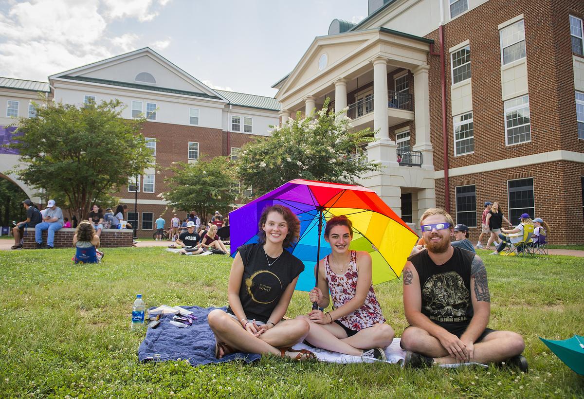 Honors students sitting outside on the quad with a colorful umbrella