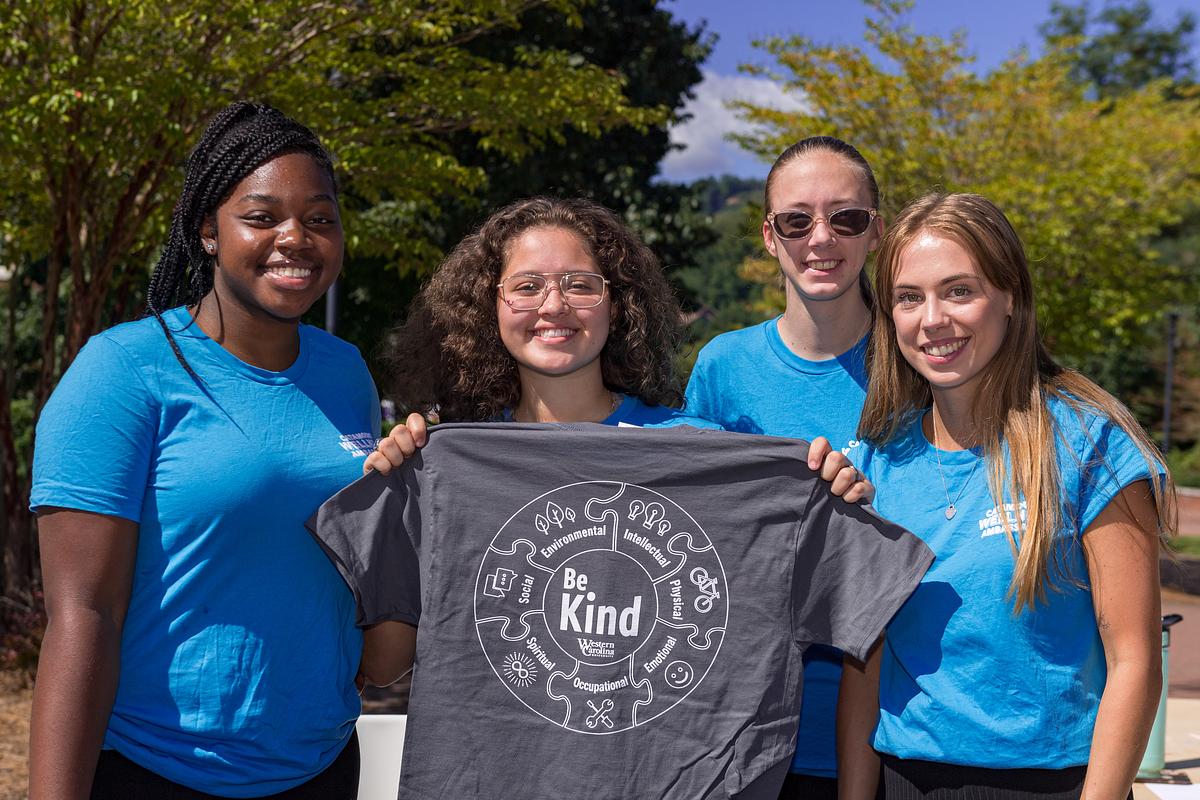 Students holding up a tshirt with the words Be Kind