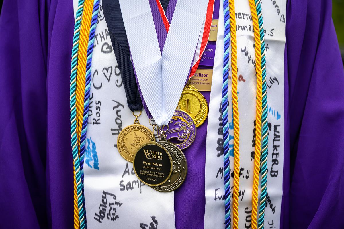 Graduating student wearing multiple medals and pendants