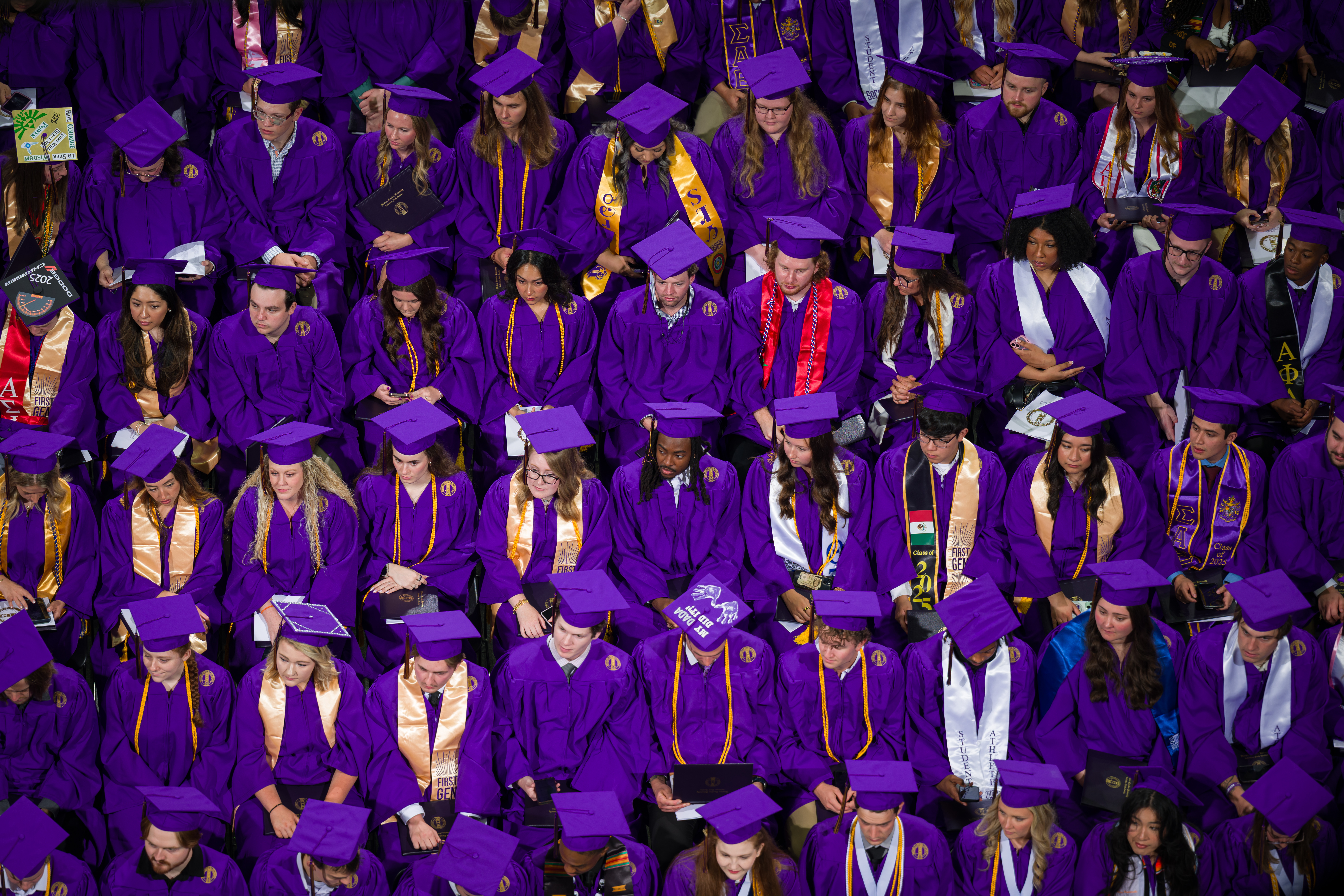 Students sitting in their gowns waiting for their diplomas at commencement