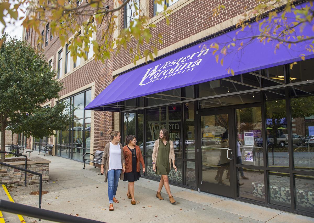 Graduate students stand talking outside of the WCU instructional entrance in Asheville
