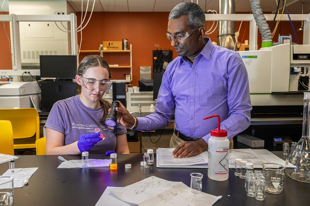Professor assisting a student conduct an experiment in a lab