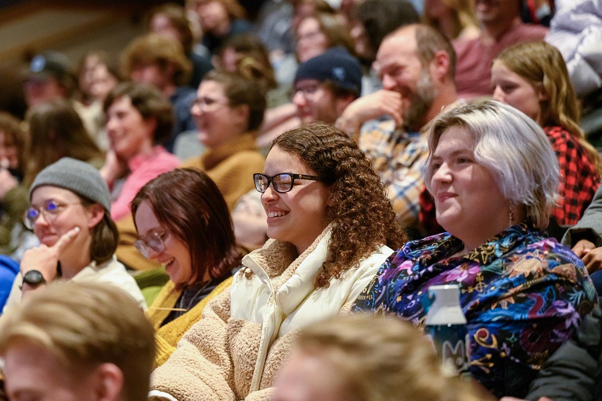 Audience members listening to a speech and laughing at a joke