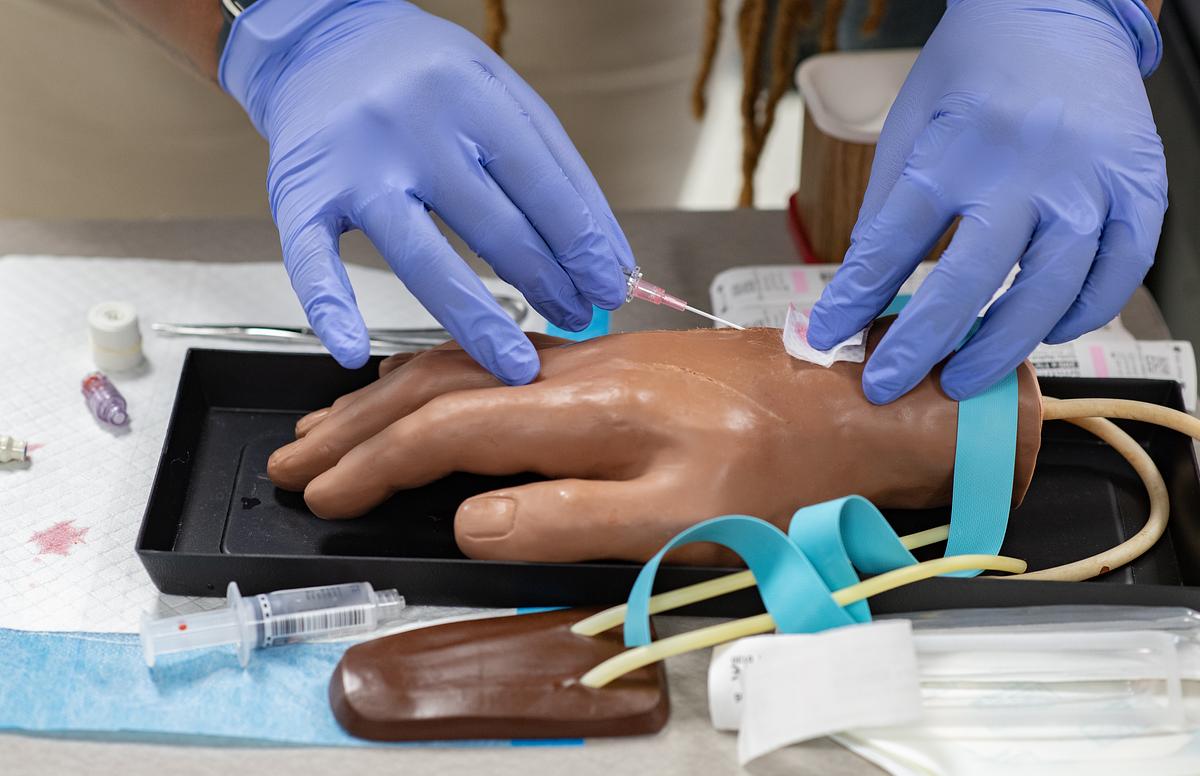 Nursing student working on a plastic hand for a medical training session