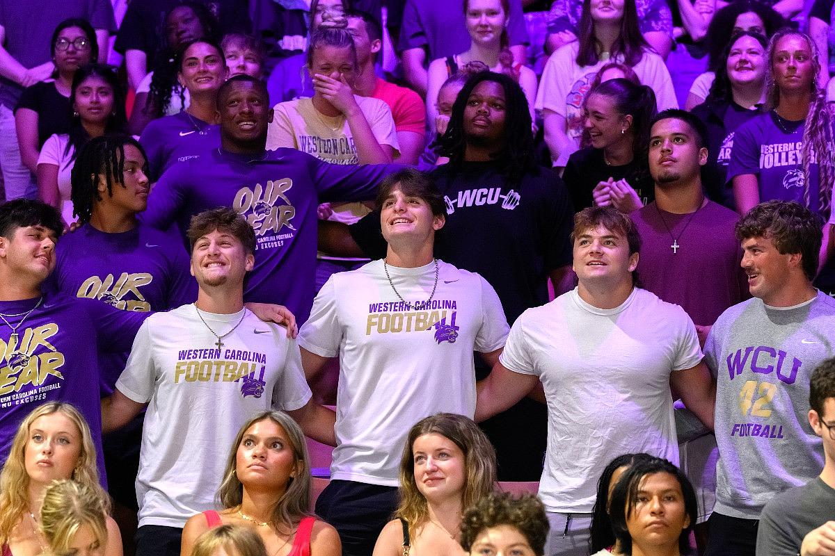 Group of 91Ů�� football fans wearing purple and white team apparel at stadium event.
