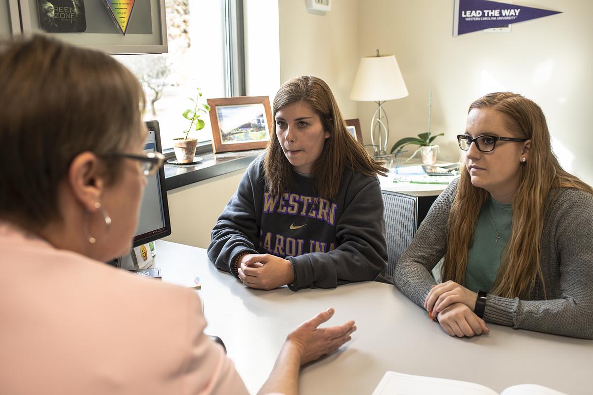 Woman showing a booklet to a student at a table