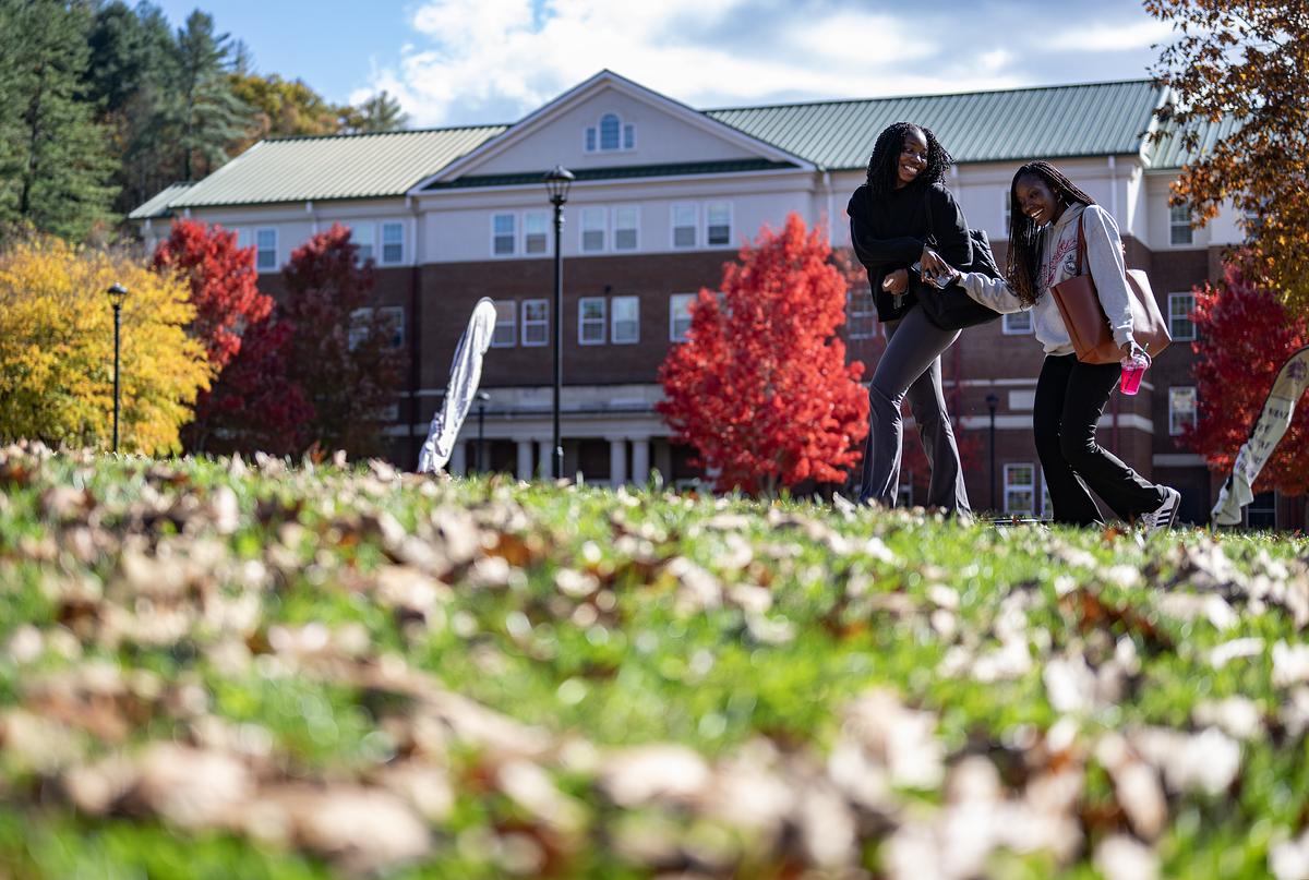Students walking and laughing on campus on a beautiful fall day