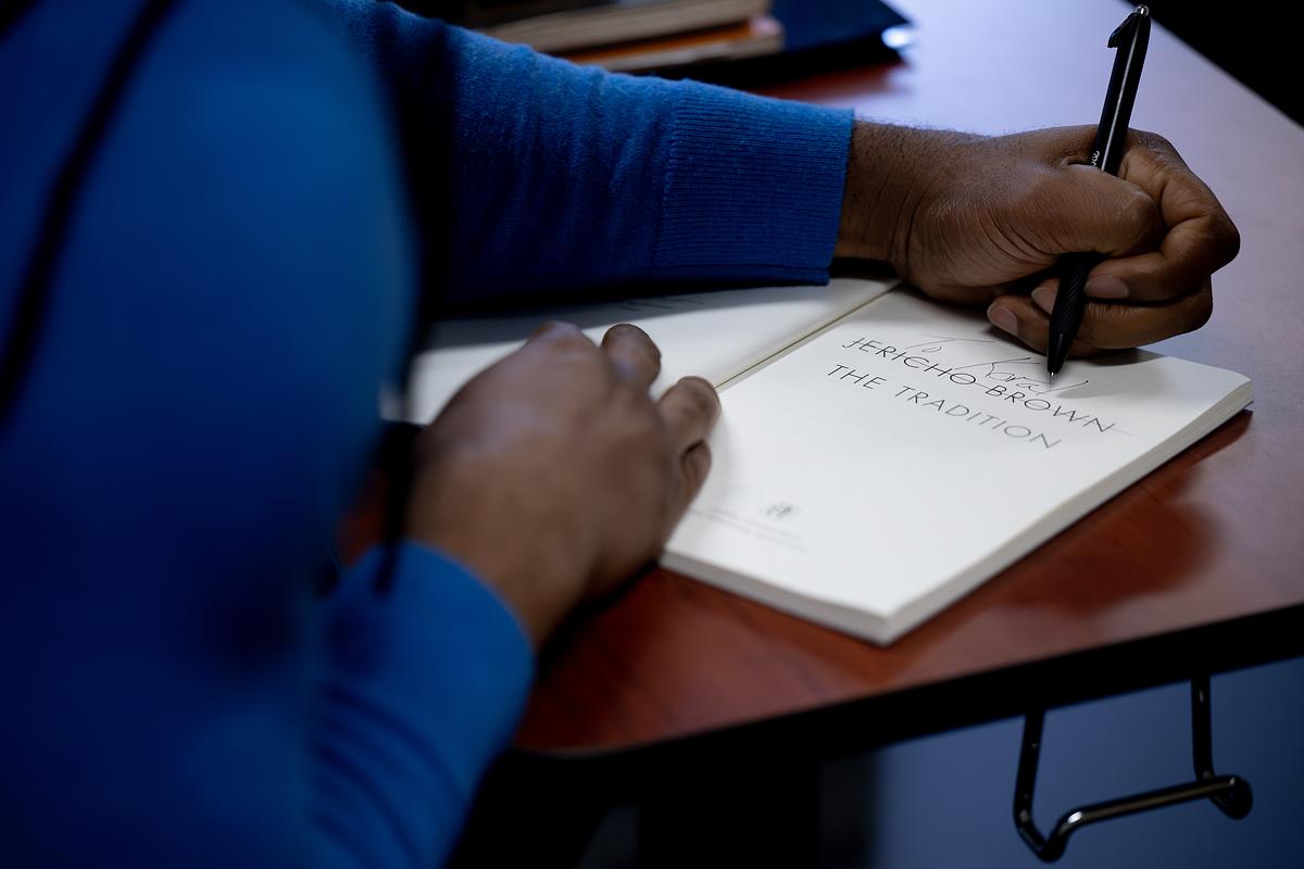 Jericho Brown signing a book at a table for Litfest