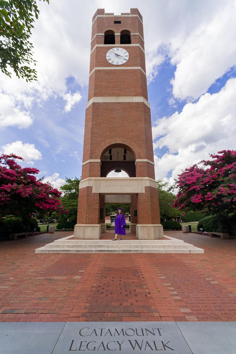 Graduate taking the Legacy Walk underneath the Alumni Tower