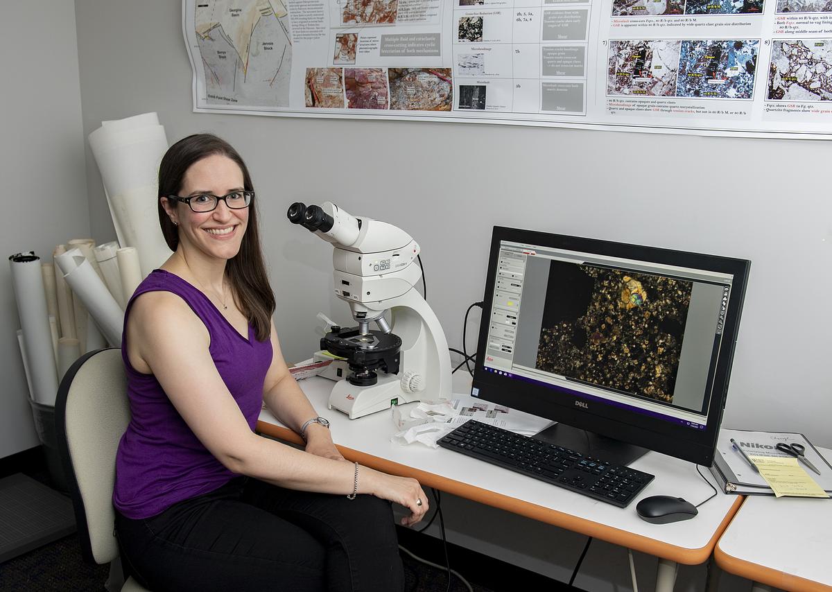Amy Fagan smiling for the camera working with a microscope and computer