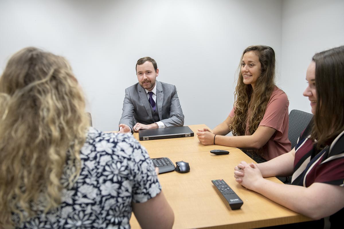 Professor David Solomon sits around a table in discussion with students