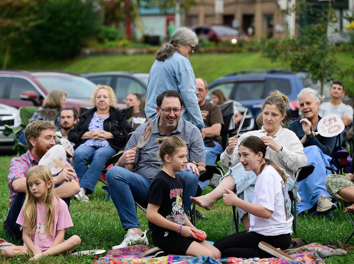 Families sitting together in the grass enjoying an event