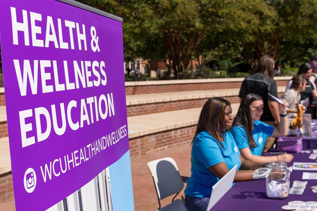 Health and Wellness staff sitting at a table waiting for students to interact with at the Health and Wellness fair